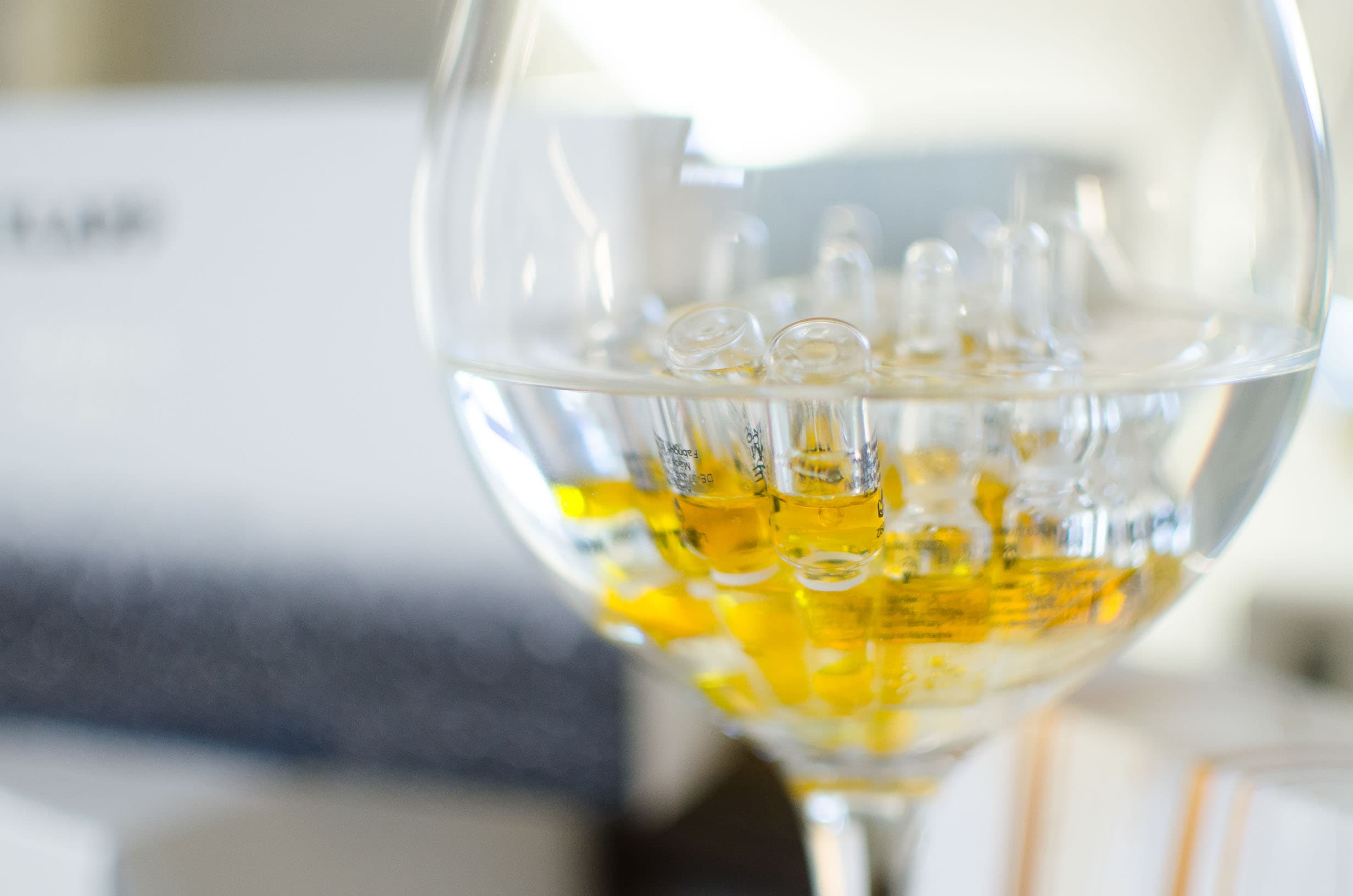 Ampullen mit goldgelbem Inhalt in einem großen Stielglas
